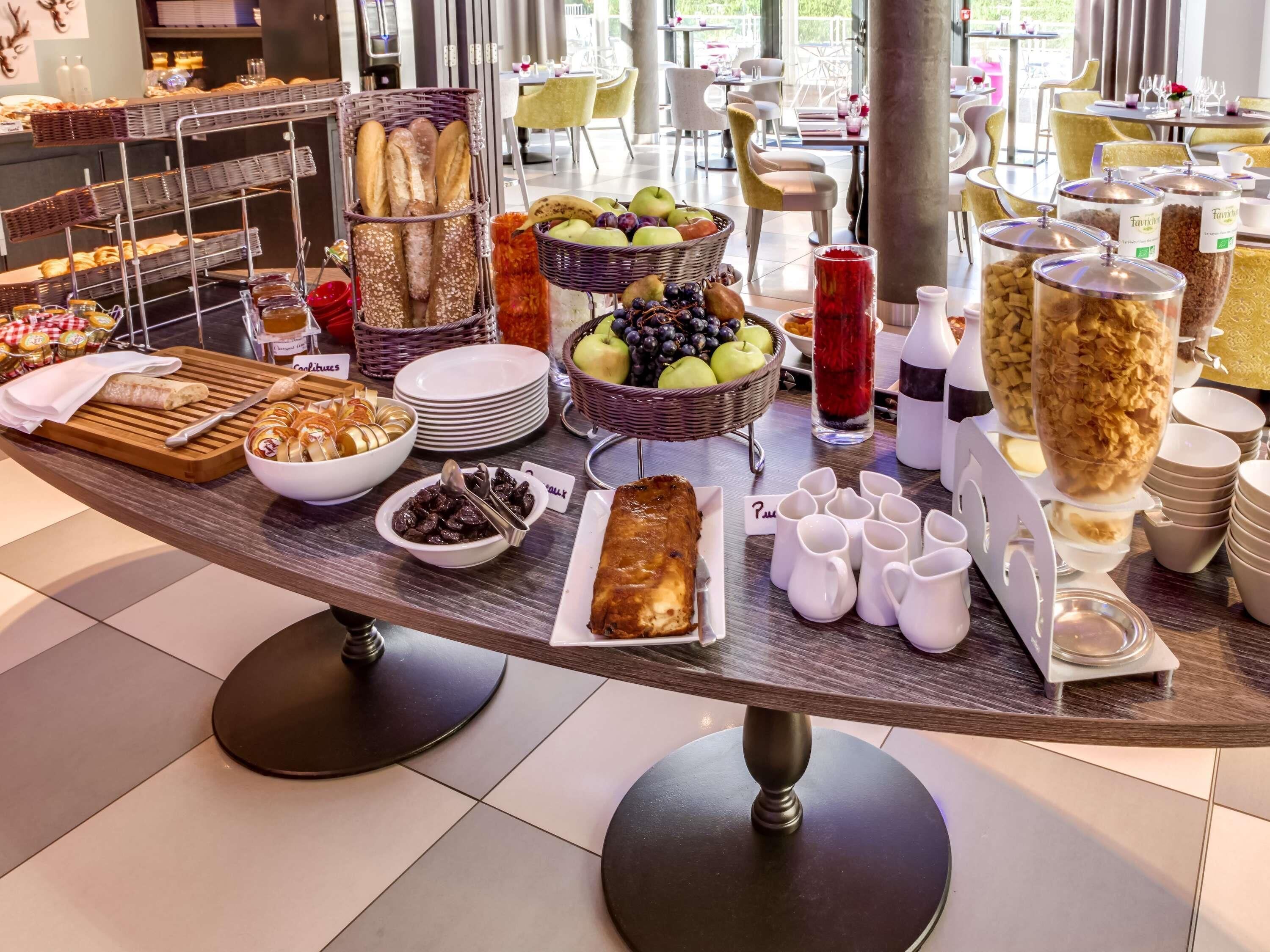 Una mesa de buffet con diversos alimentos, como pan, frutas y bebidas.