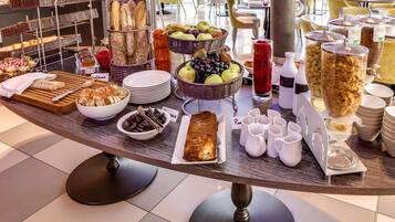Una mesa de buffet con diversos alimentos, como pan, frutas y bebidas.