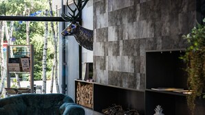 Un interior moderno con un venado montado en la pared, una chimenea y una estantería con libros y objetos decorativos.