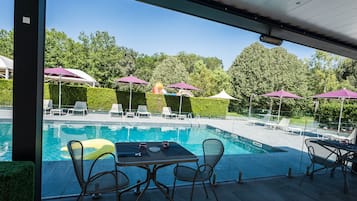 Relax by the serene pool surrounded by lush greenery and comfortable lounge chairs.