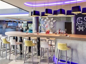 A modern bar area with a central counter, bar stools, and pendant lighting.