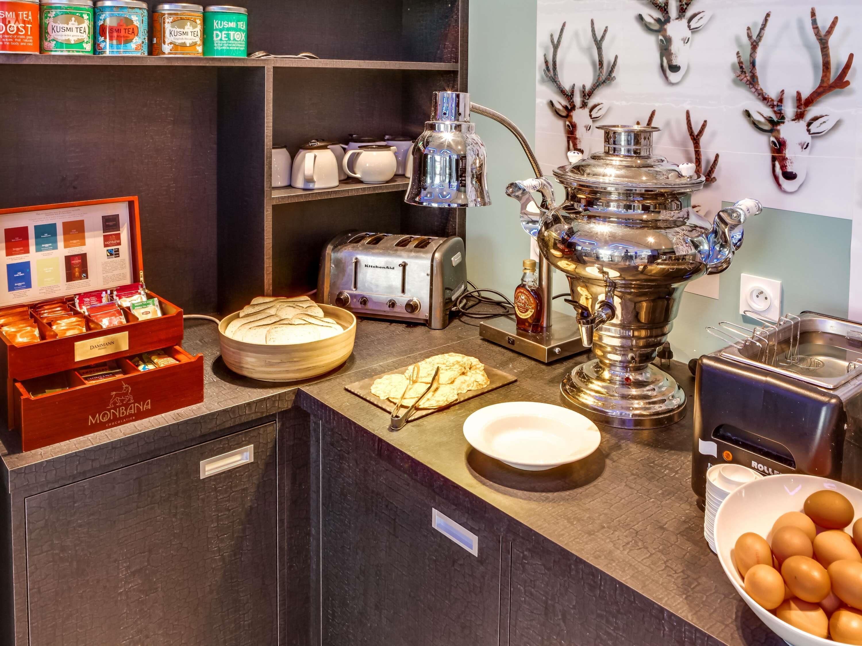 A buffet area with various food items, a kettle, a toaster, and decorative deer heads on the wall.
