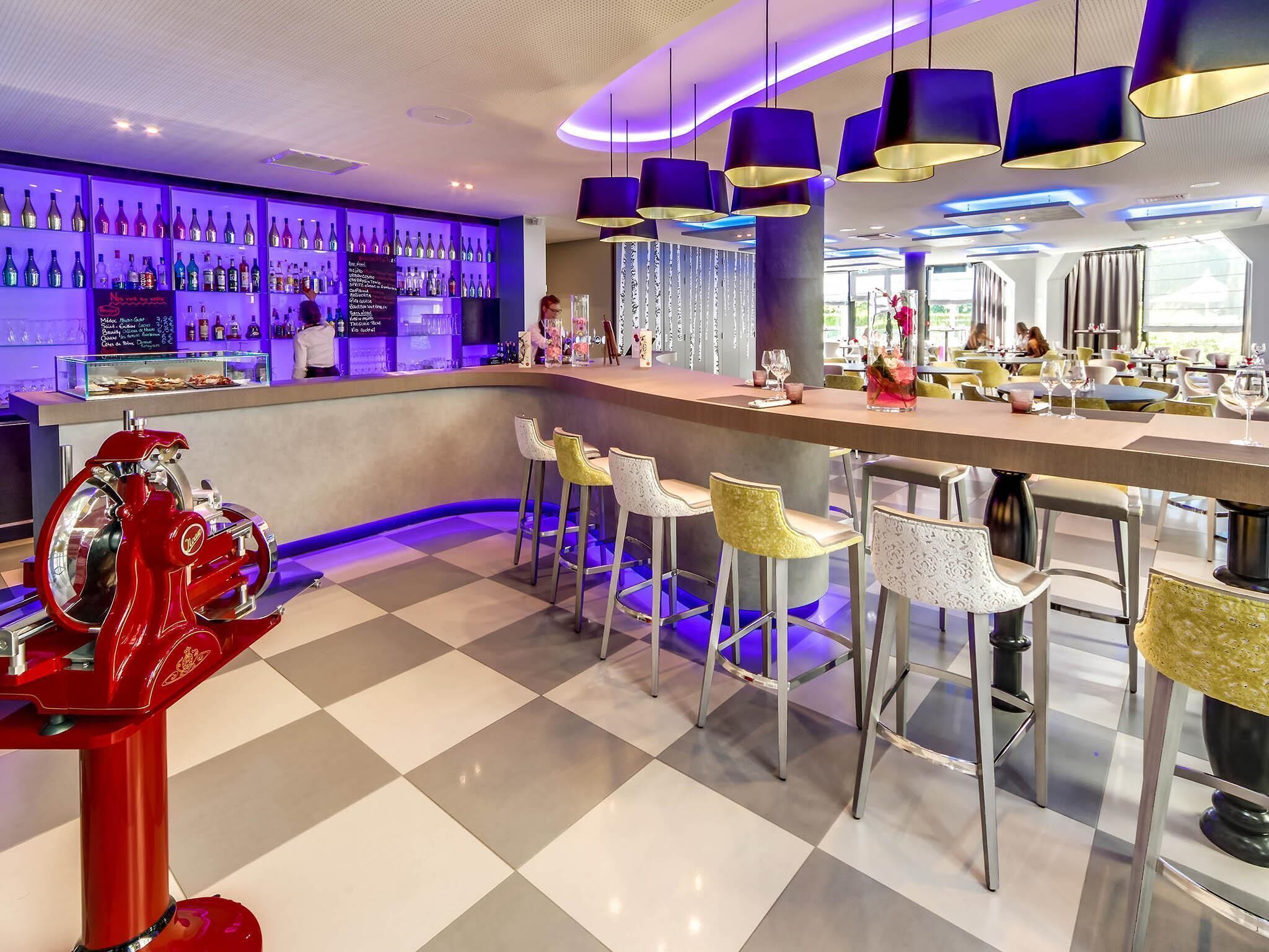 Un espace bar avec un sol à carreaux, des tabourets de bar et une machine rouge.