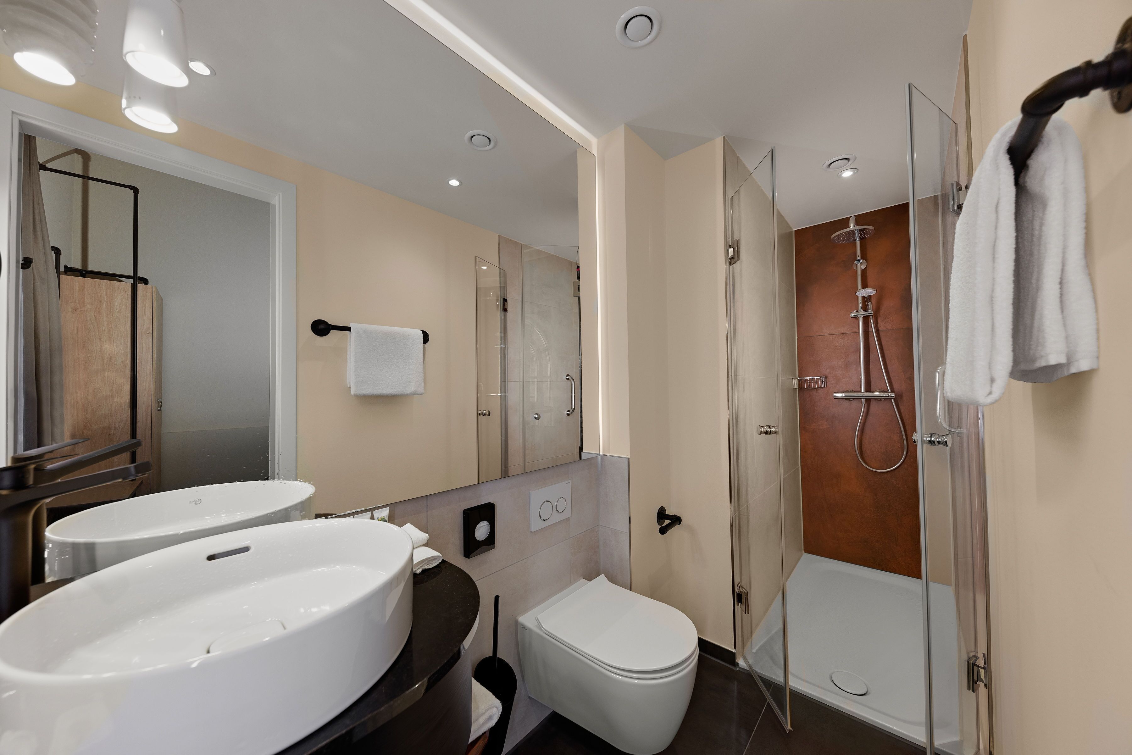 Une salle de bain moderne avec deux lavabos, des toilettes et une douche à l’italienne.