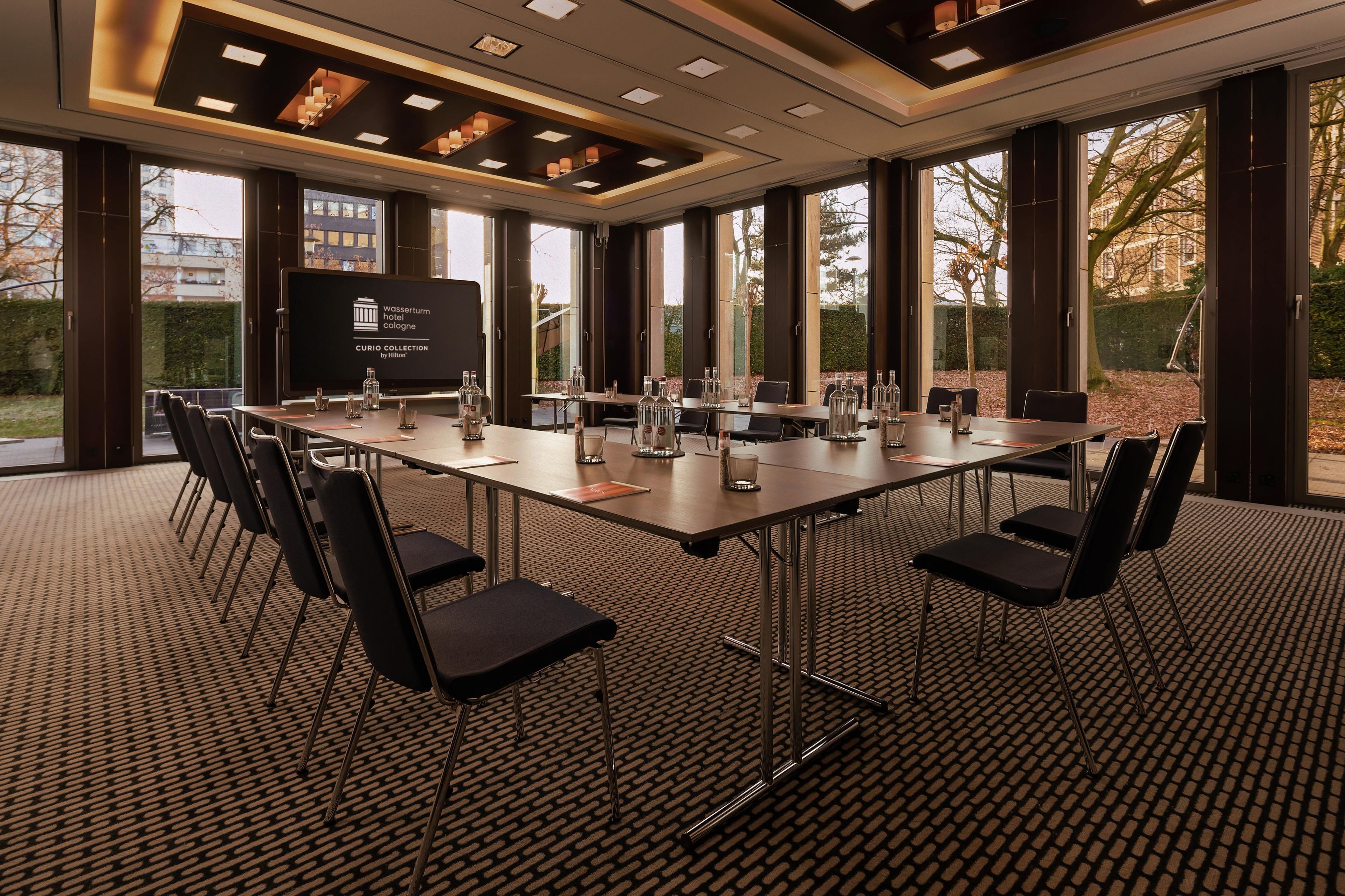 Une salle de conférence équipée d’une longue table, de chaises et d’un écran de présentation.