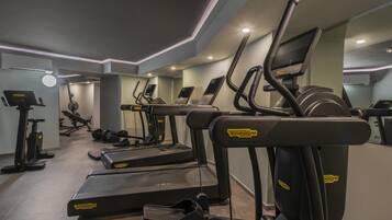 Une salle de sport équipée de tapis de course, de vélos elliptiques et d’un banc de musculation.
