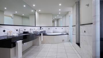 A modern bathroom with a large mirror, two sinks, a bathtub, and a shower area.