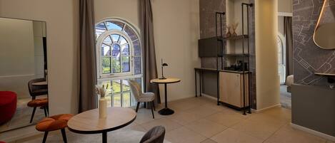 A modern living room with a dining area, a kitchen, and a large window with curtains.