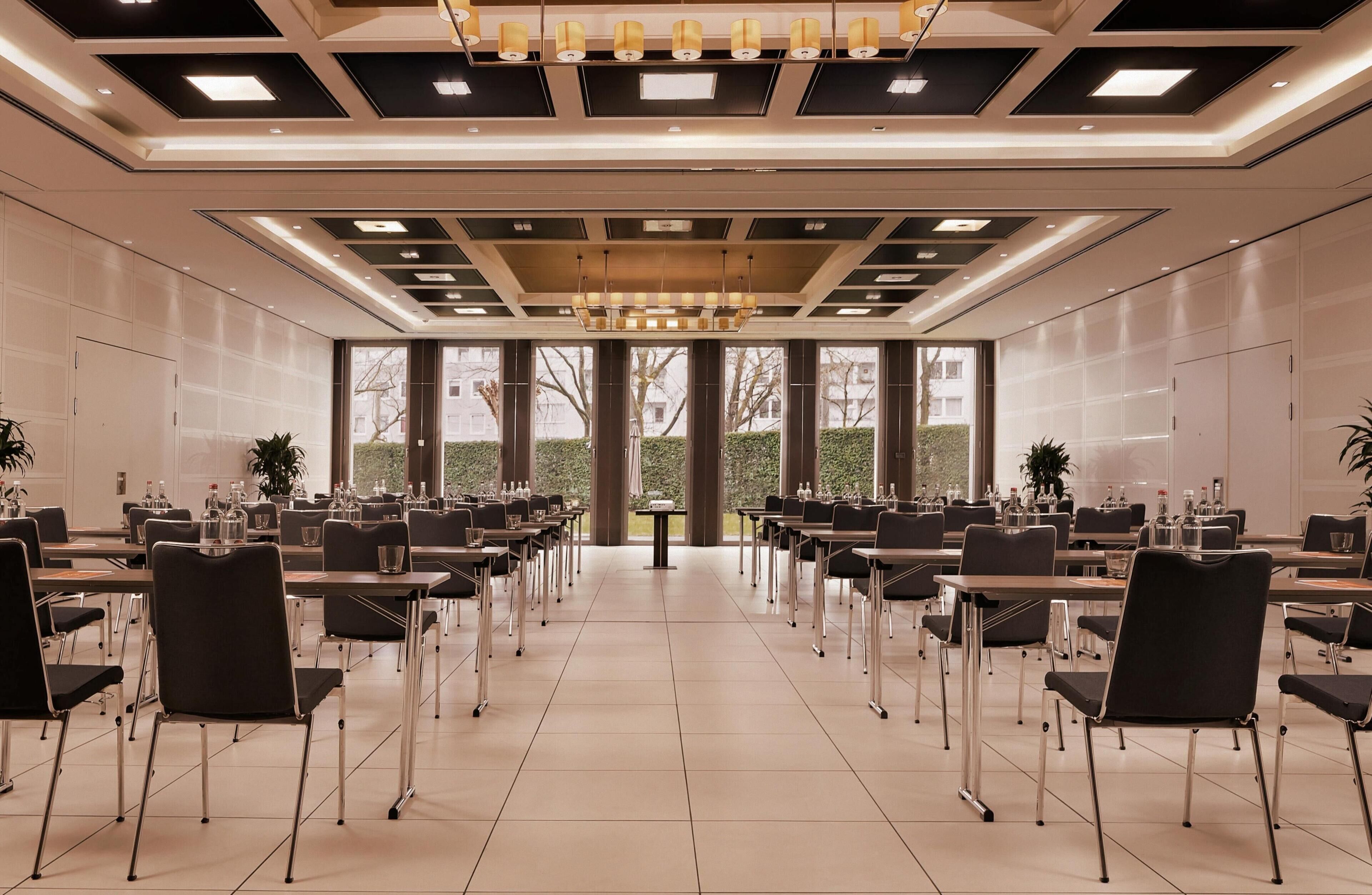 A conference room with tables and chairs, large windows, and a modern ceiling design.