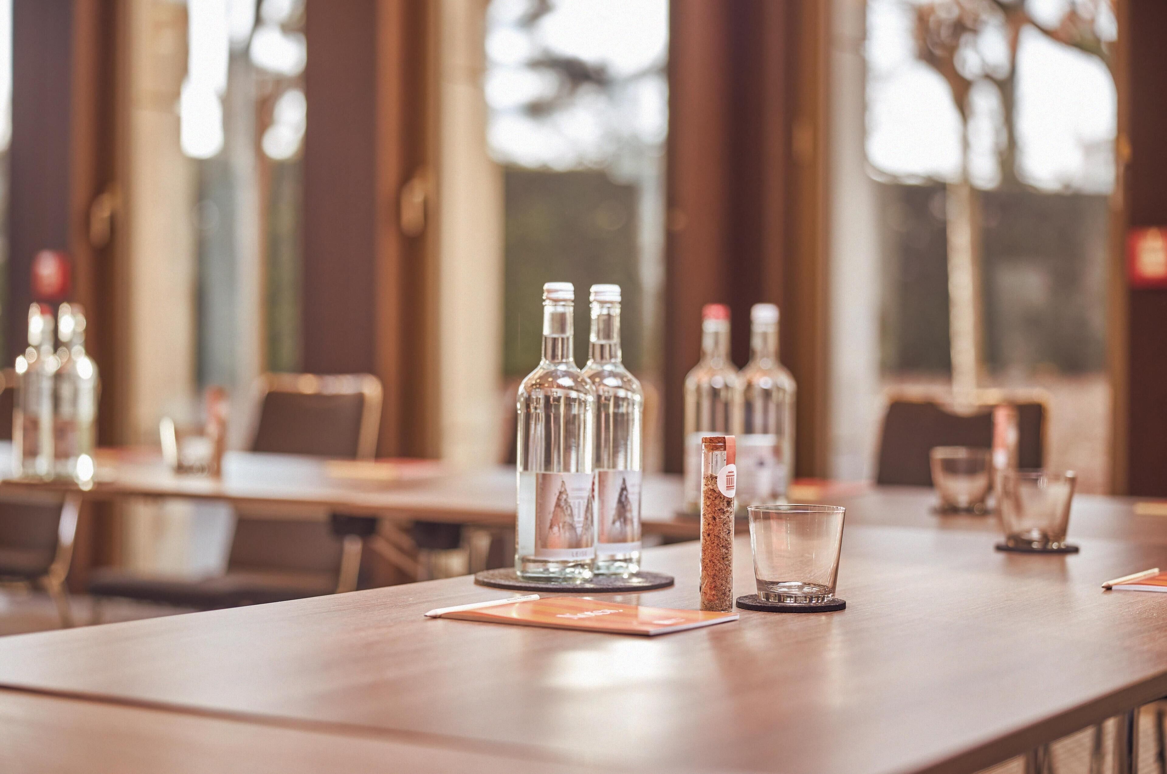 A restaurant setting with tables, clear glass bottles, and a menu.