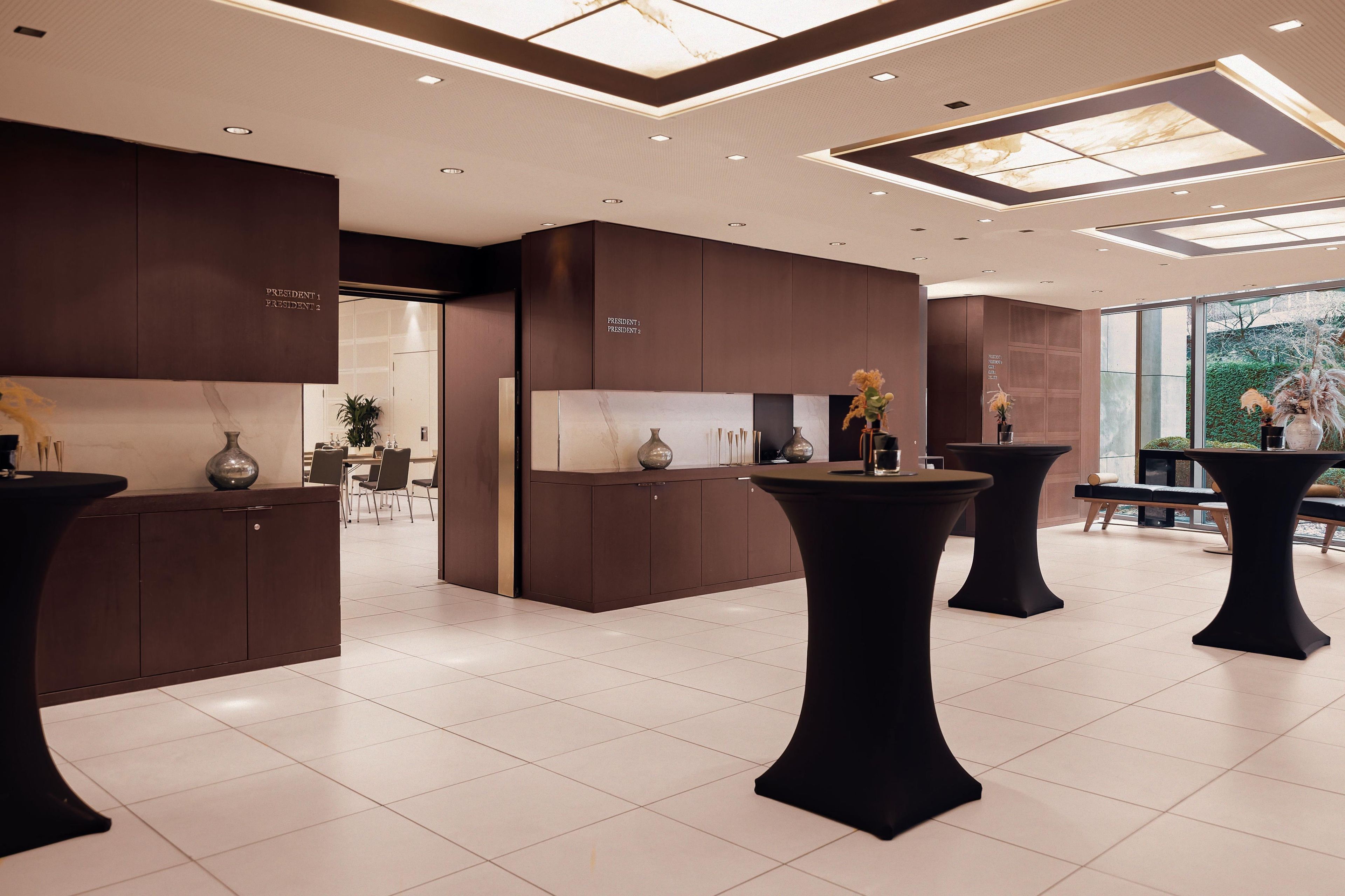 A modern interior with dark wood cabinetry, a central island, and black tables.