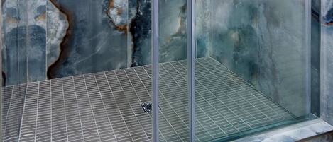 A glass-enclosed shower with a marble-like wall design.
