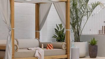 A wooden daybed with a canopy, positioned by a poolside.