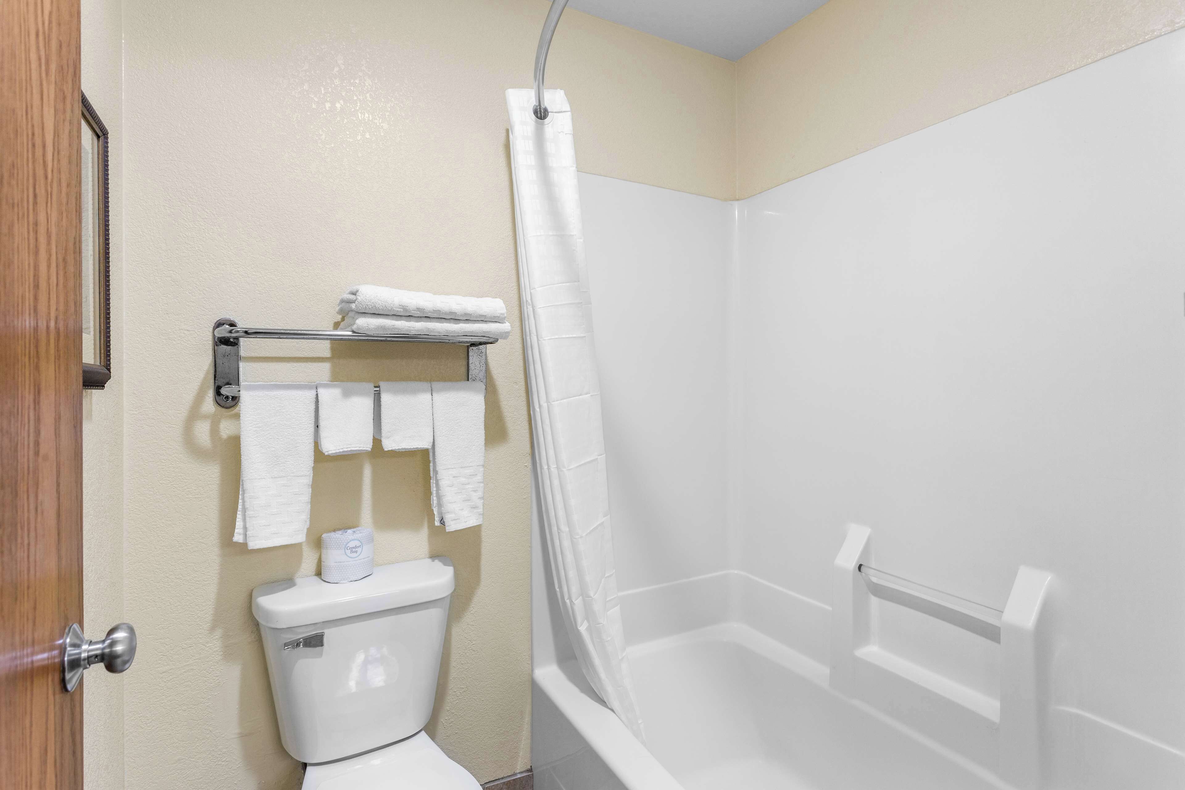 Ein Badezimmer mit Toilette, einem Handtuchhalter mit mehreren Handtüchern und einer Badewanne.