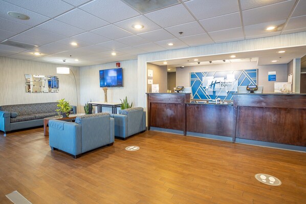 A hotel lobby with a reception desk, seating area, and a television mounted on the wall. - Holiday Inn Express Newark Airport Elizabeth by IHG (Elizabeth)