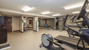 Een fitnessruimte met loopbanden, hometrainers en krachttoestellen.