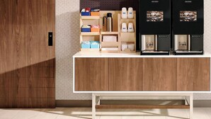 Een moderne keuken met houten kastjes, een wit aanrecht en twee koffieapparaten.