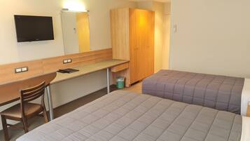 Ett hotellrum med en säng, ett skrivbord med en stol, en garderob, en tv och en luftkonditioneringsanläggning.