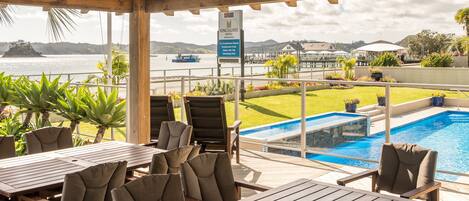 A covered outdoor area with a pool, lounge chairs, and a sign for Kingsgate Hotel.