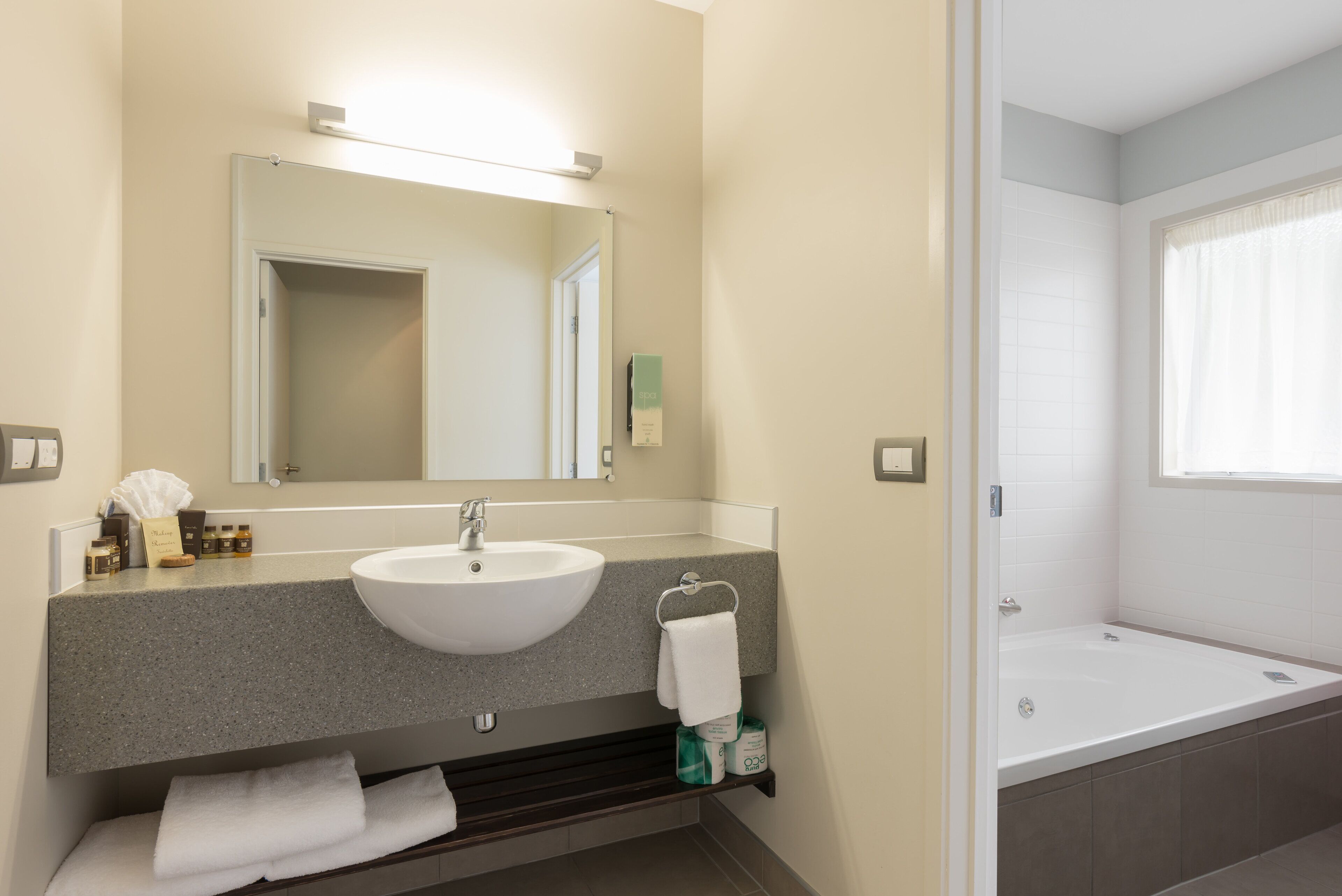 A modern bathroom with a large sink, mirror, and bathtub.