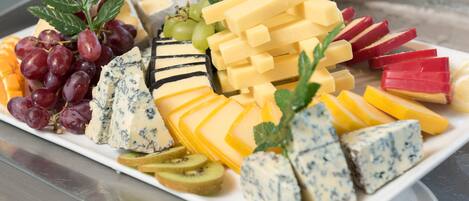 A variety of cheeses, fruits, and garnishes on a white platter.
