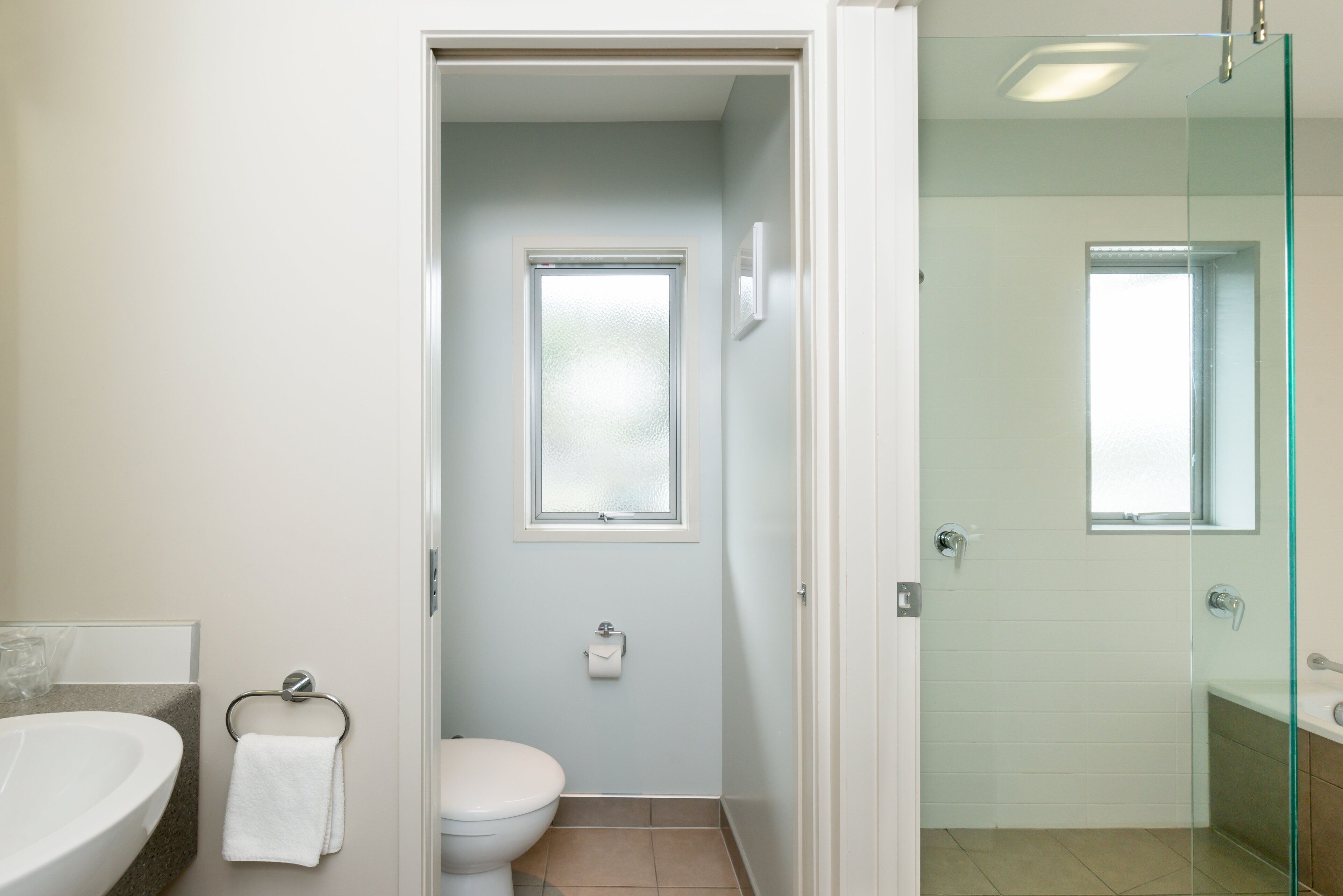 A bathroom with a toilet, a sink, and a glass shower enclosure.