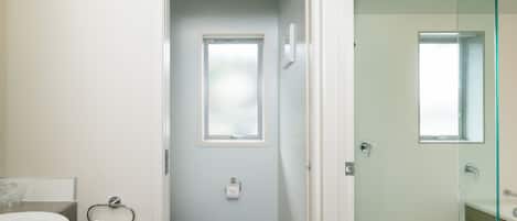 A bathroom with a toilet, a sink, and a glass shower enclosure.