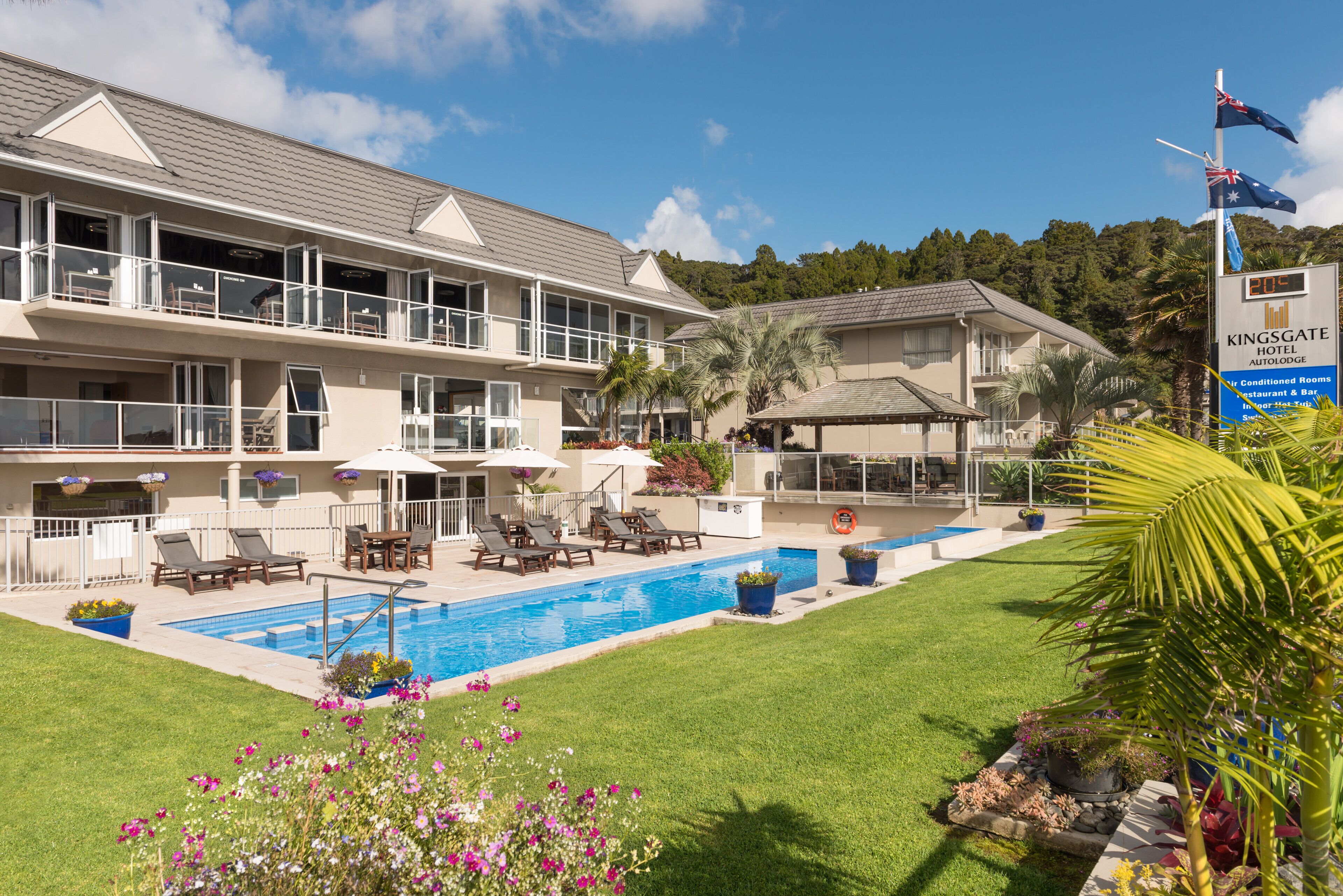 A hotel with a swimming pool, outdoor seating, and a flag.