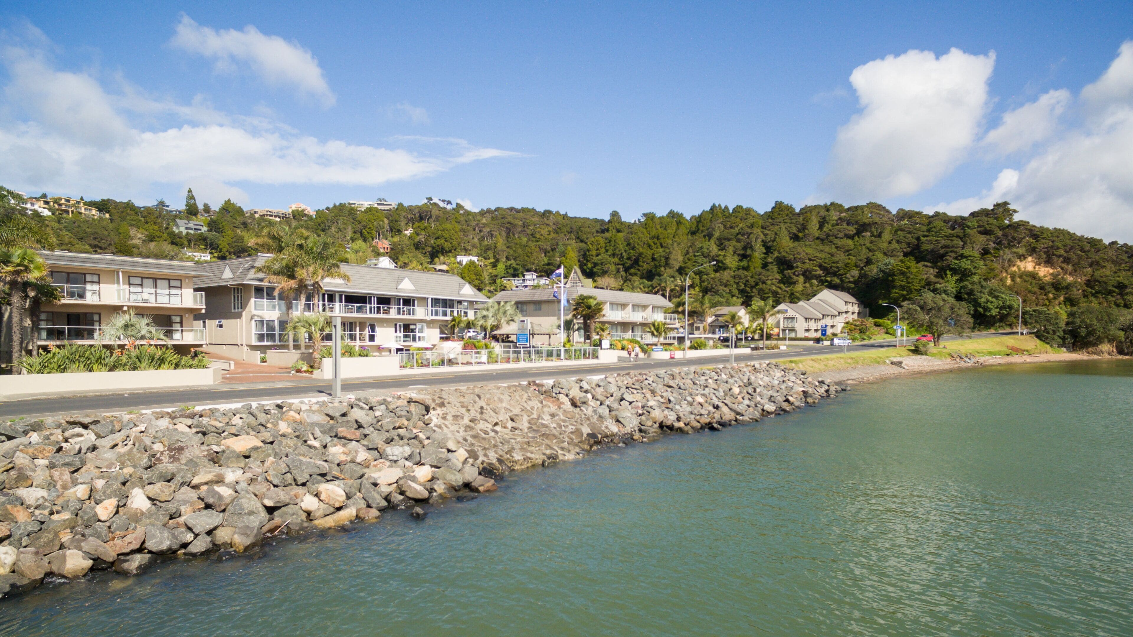 Ein Küstenhotel mit mehreren Gebäuden, einem Felssteg und freiem Blick auf das Wasser.