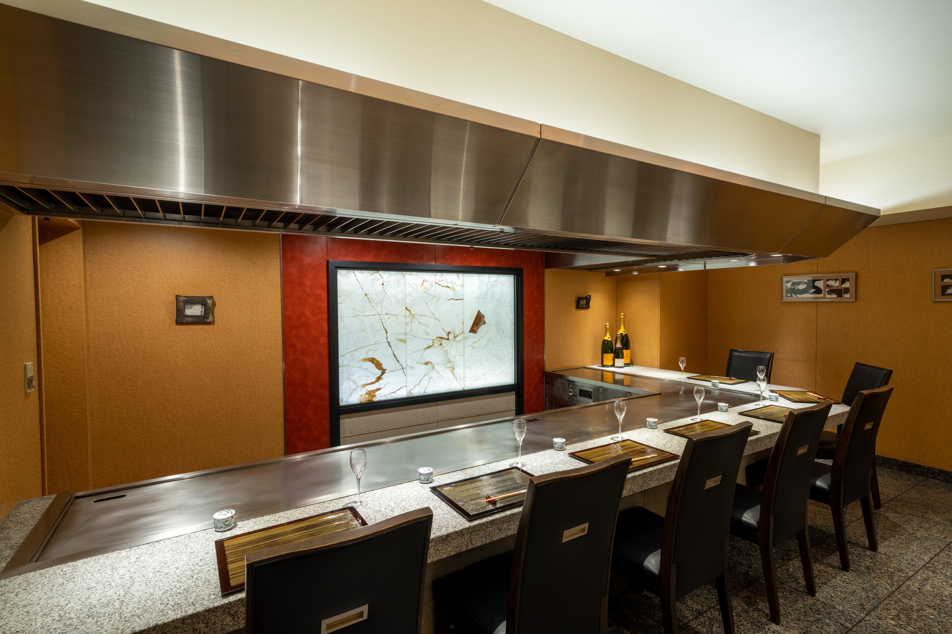 Un salón de conferencias con una larga mesa, sillas, un ventanal con vistas y una cocina moderna con electrodomésticos de acero inoxidable.