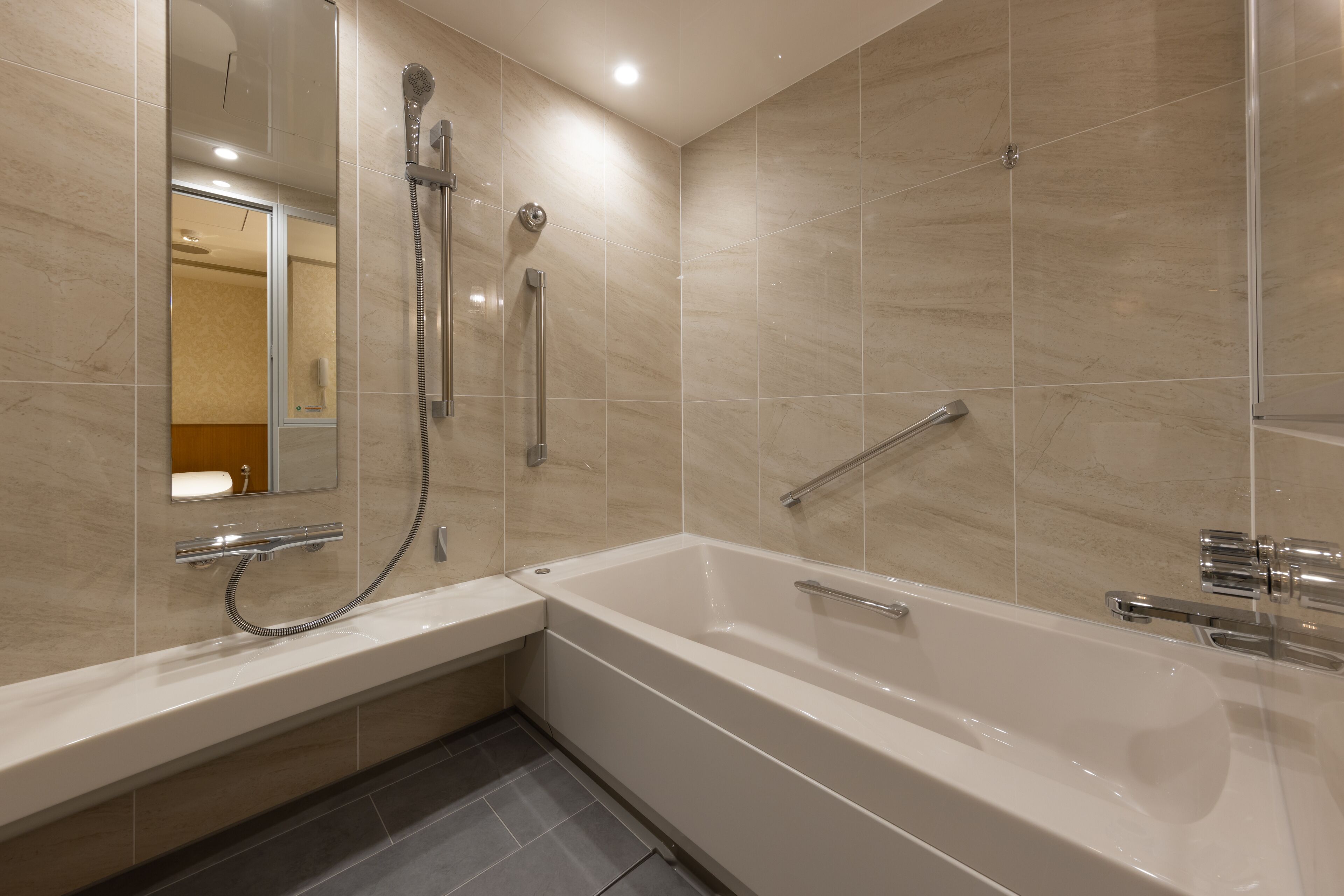 Une salle de bain moderne équipée d’une baignoire, d’une douche et d’une barre d’appui.