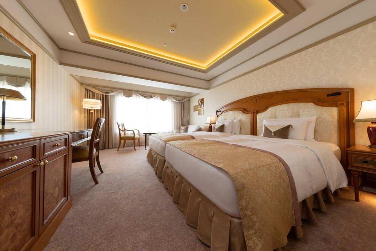 A hotel room with a large bed, a desk, a chair, and a nightstand.