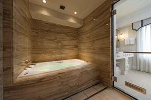 Une salle de bain moderne avec une baignoire sur pieds, des murs en marbre et une douche à parois de verre.