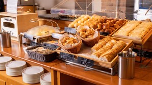 A bakery display with various breads and pastries, including croissants and baguettes, in wicker baskets and trays. - Hotel Nikko Princess Kyoto (Kyoto)
