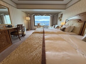 Une chambre d’hôtel avec deux lits, un bureau, une chaise et une vue sur la ville.