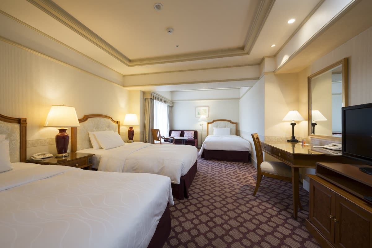 A hotel room with two beds, a desk, a chair, a television, and a mirror.