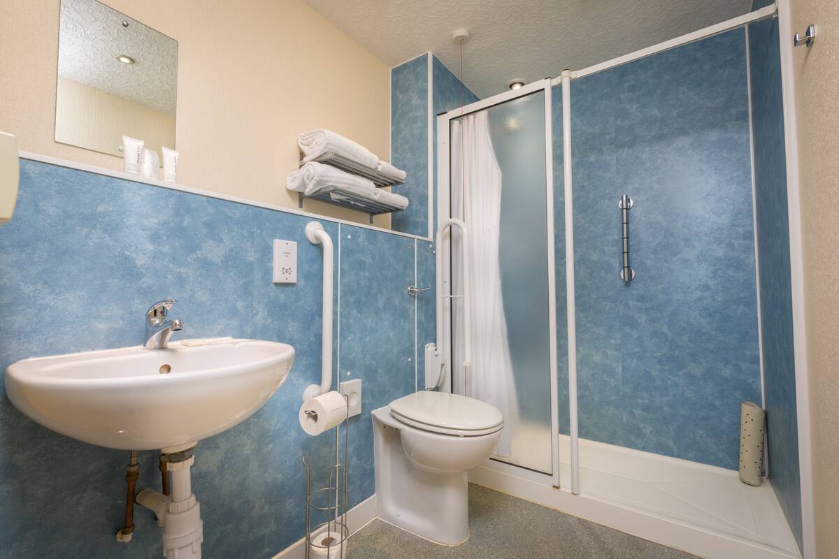 Une salle de bain équipée d’un lavabo, de toilettes et d’une douche à parois en verre.