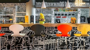 Un espace bar agrémenté d’un néon, de tabourets et d’un mur orné de motifs.