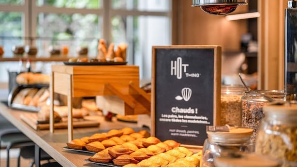 Un comptoir de boulangerie où sont exposés divers produits de boulangerie, avec une pancarte indiquant « NOUVELLE PÉTRISSE ».