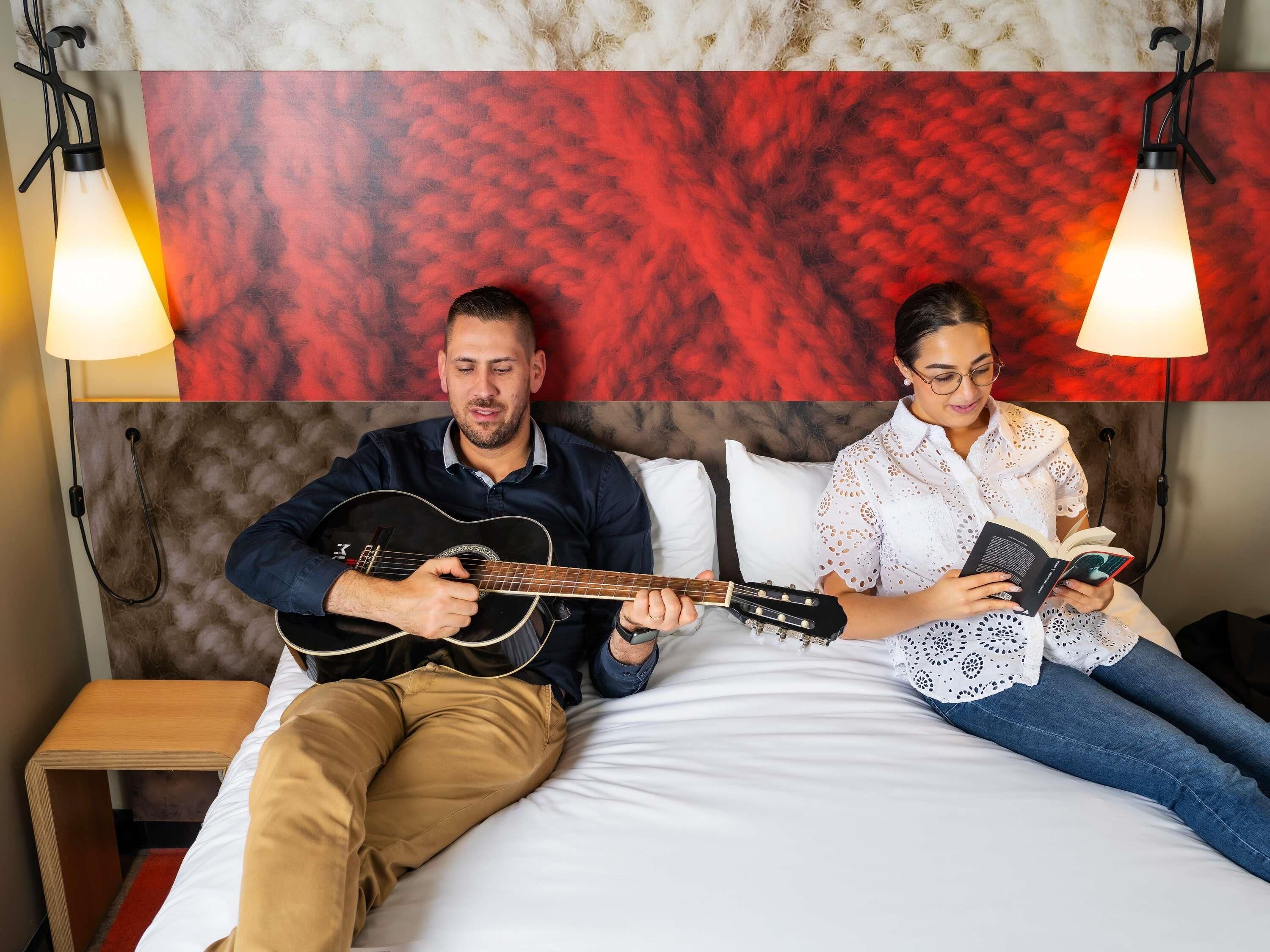 Ein Zimmer mit einem Bett, einem Nachttisch und einem Kopfstück mit einem roten abstrakten Muster.