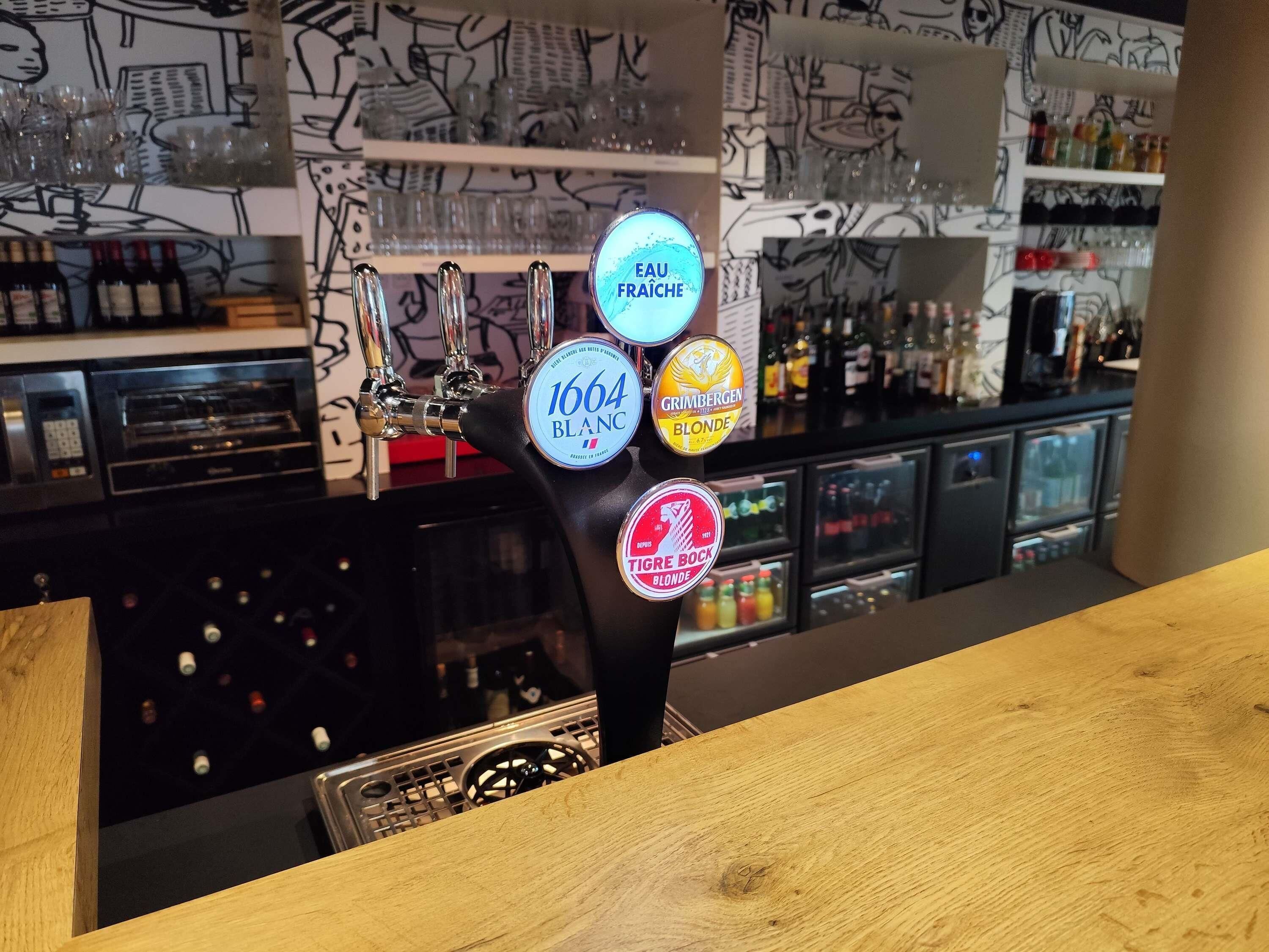 Un bar où l’on peut voir, sur le robinet, les mentions « 1664 Blanc » et « Grimbergen Blonde ».