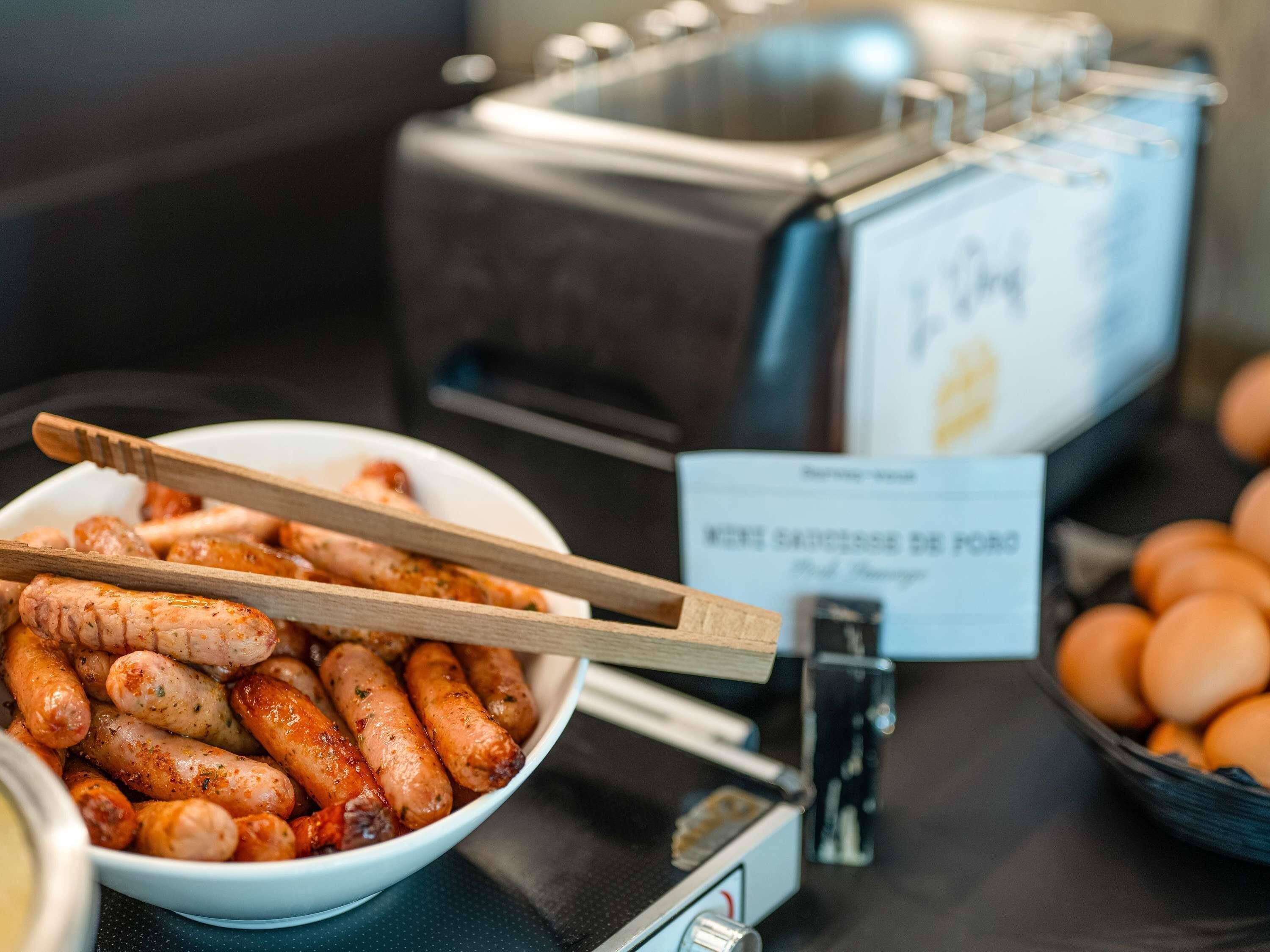 A buffet with a bowl of sausages and a sign indicating a pork dish.
