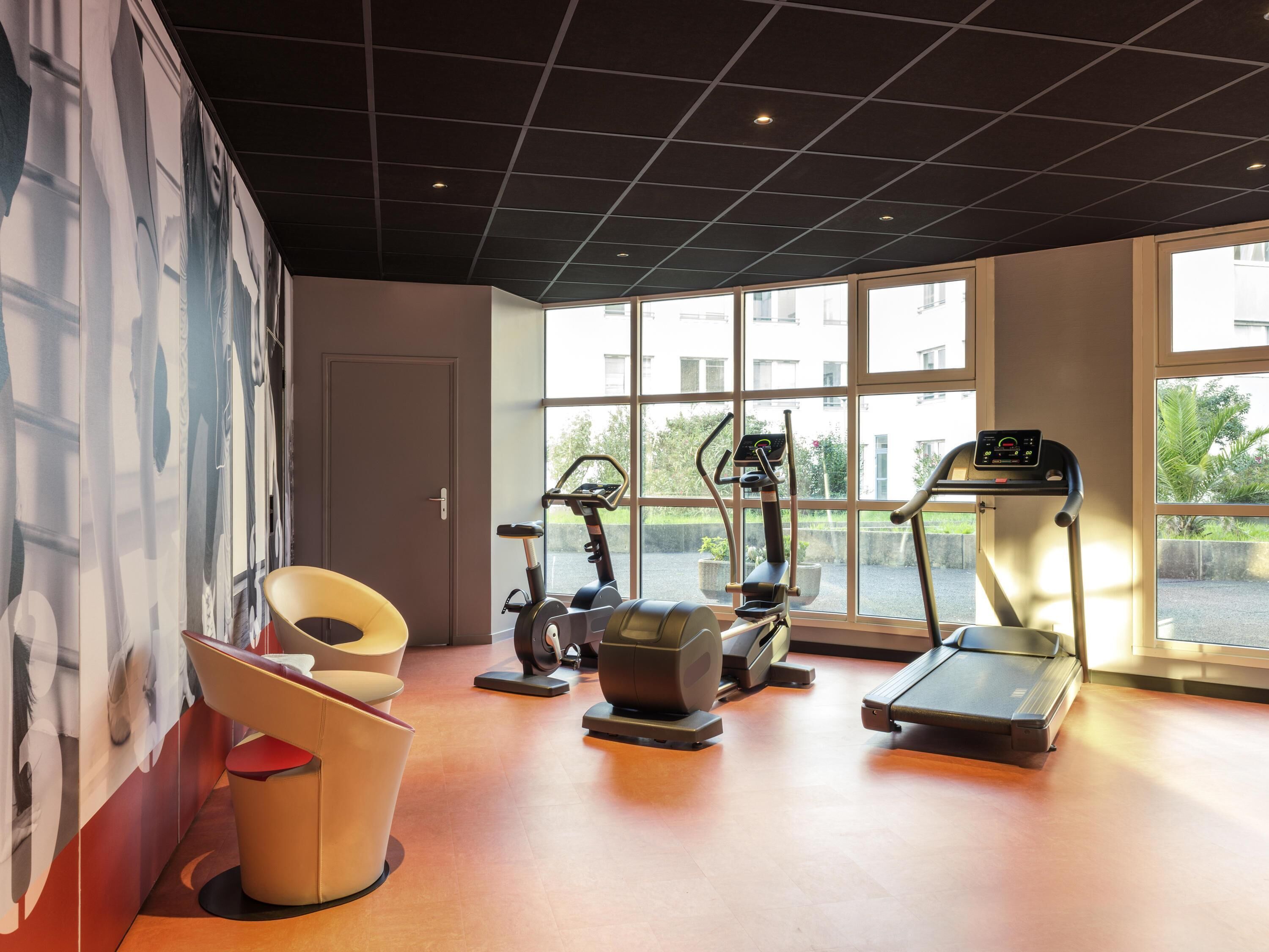 Een fitnessruimte met trainingsapparatuur, grote ramen en een modern design.