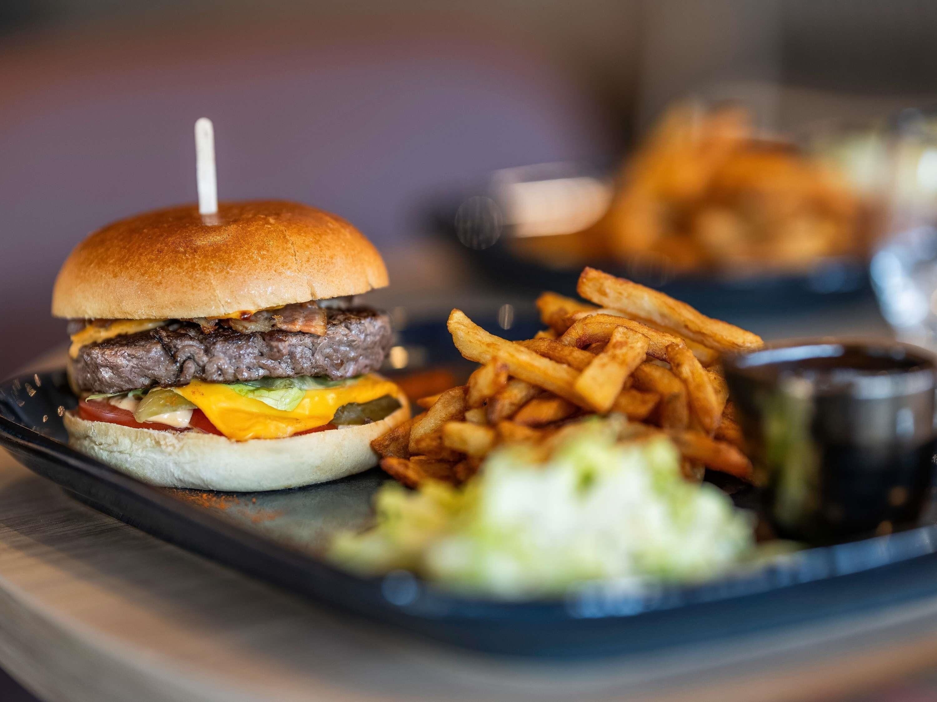 Un hamburger accompagné de frites et d’une salade, le tout servi sur une assiette.