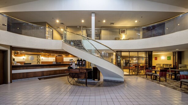 A spacious lobby with a central spiral staircase, a reception desk, and seating areas. - Comfort Inn Hall of Fame (Canton)