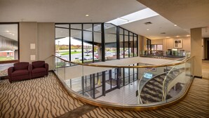 A hotel lobby with a glass railing, a curved staircase, and a view of the parking lot. - Comfort Inn Hall of Fame (Canton)