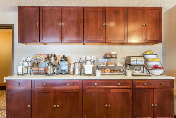 A kitchen with wooden cabinets, a countertop with various appliances, and a fruit bowl.