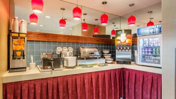 A breakfast bar with a coffee machine, a fruit display, and a refrigerator.