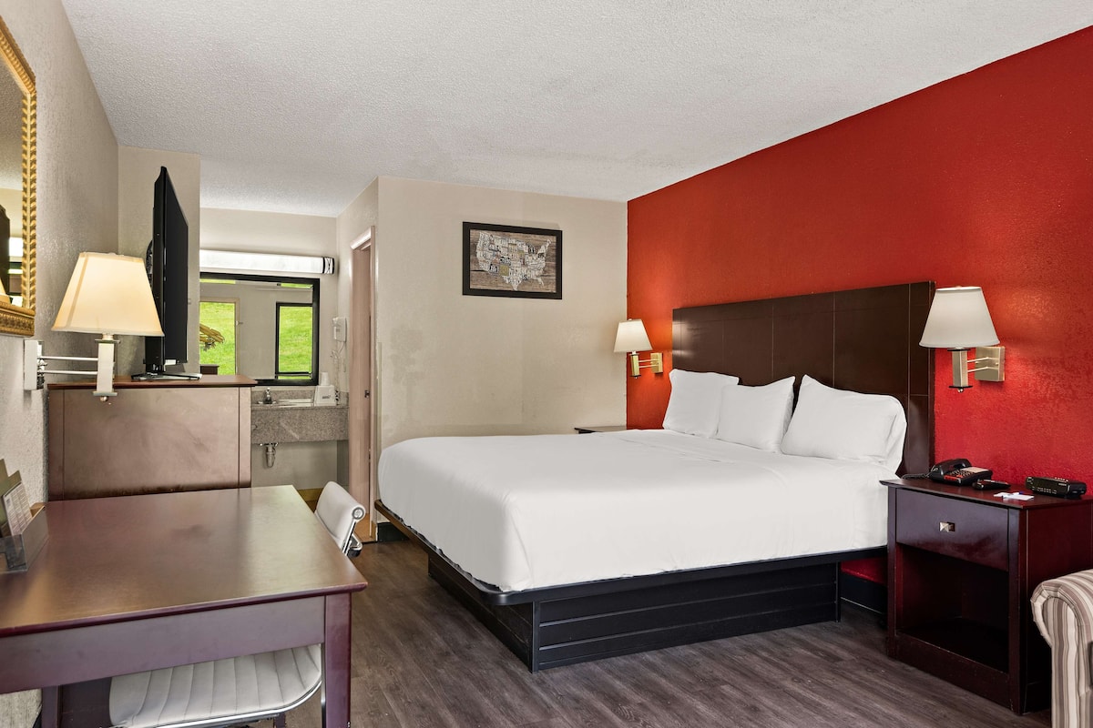 Une chambre d’hôtel comprenant un lit, des tables de chevet, un bureau et un miroir.