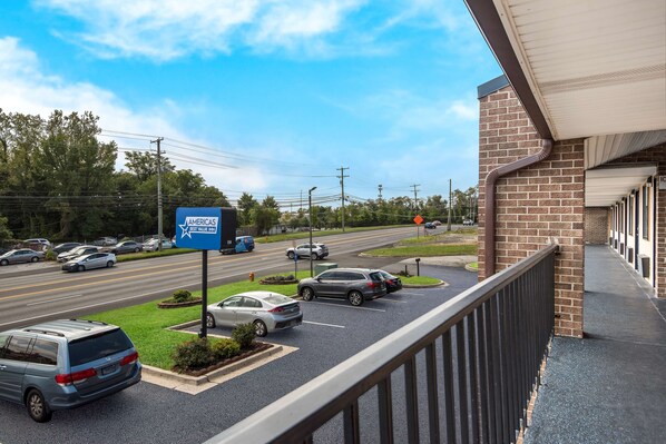 A parking lot with cars, a blue sign for AMERICAS Best Value Inn, and a building with a brick facade.